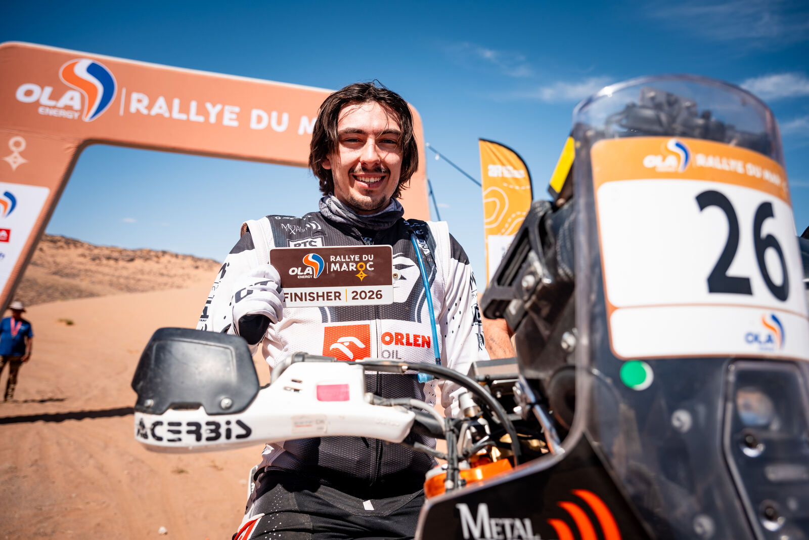 Konrad Dąbrowski with his finisher card under the Rallye du Maroc arch